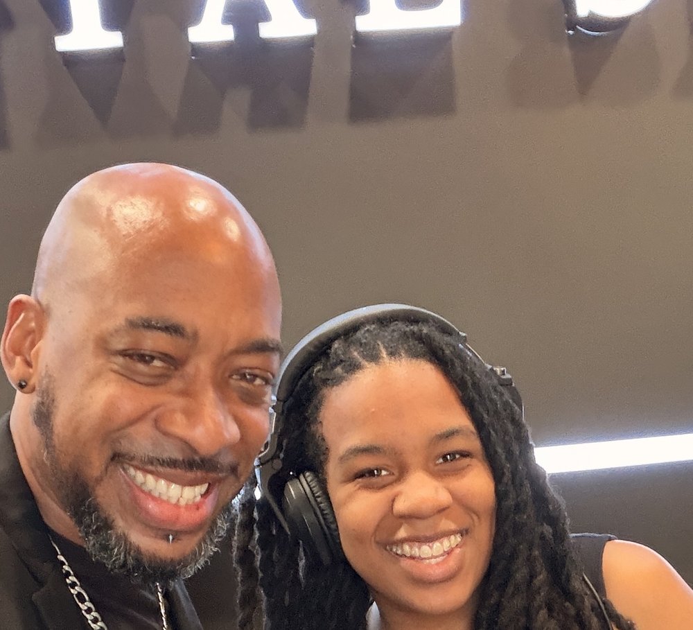 DJ Nikki G with her dad, Roy Jazz Grant, both smiling at the decks